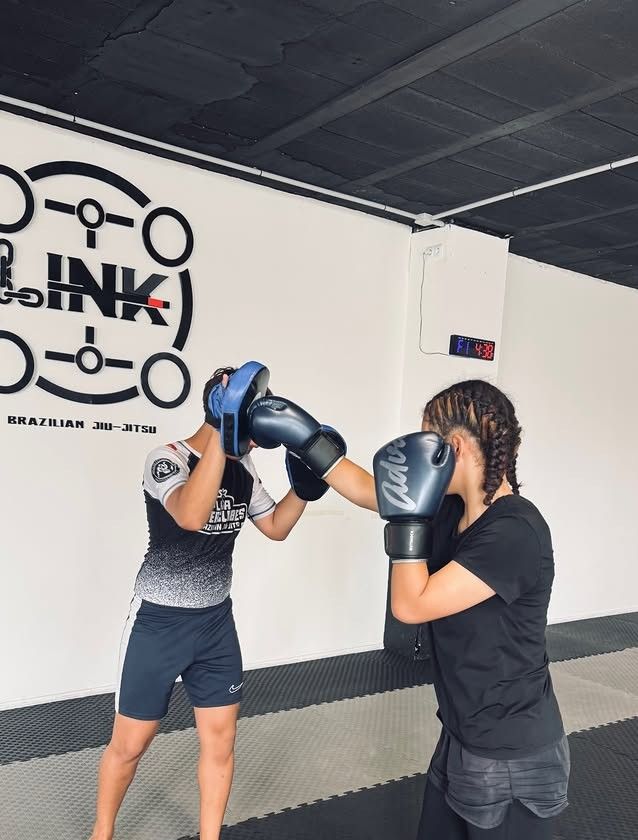 Alumna con guantes golpeando las manoplas en un entrenamiento de Muay Thai