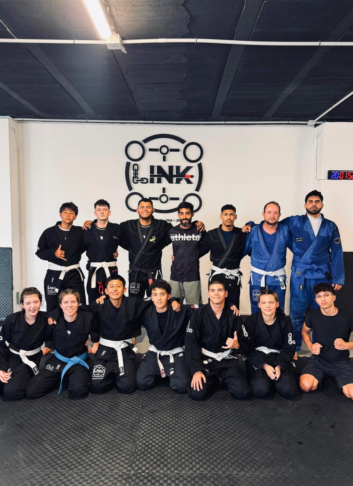 Grupo de adultos, hombres y mujeres, con kimono bajo el logo de LINK